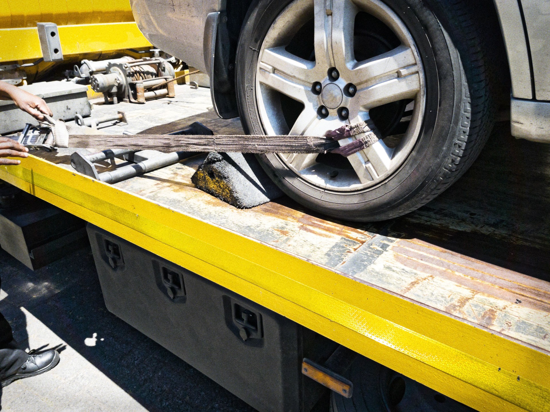 Car being secured to a flatbed tow truck after breakdown