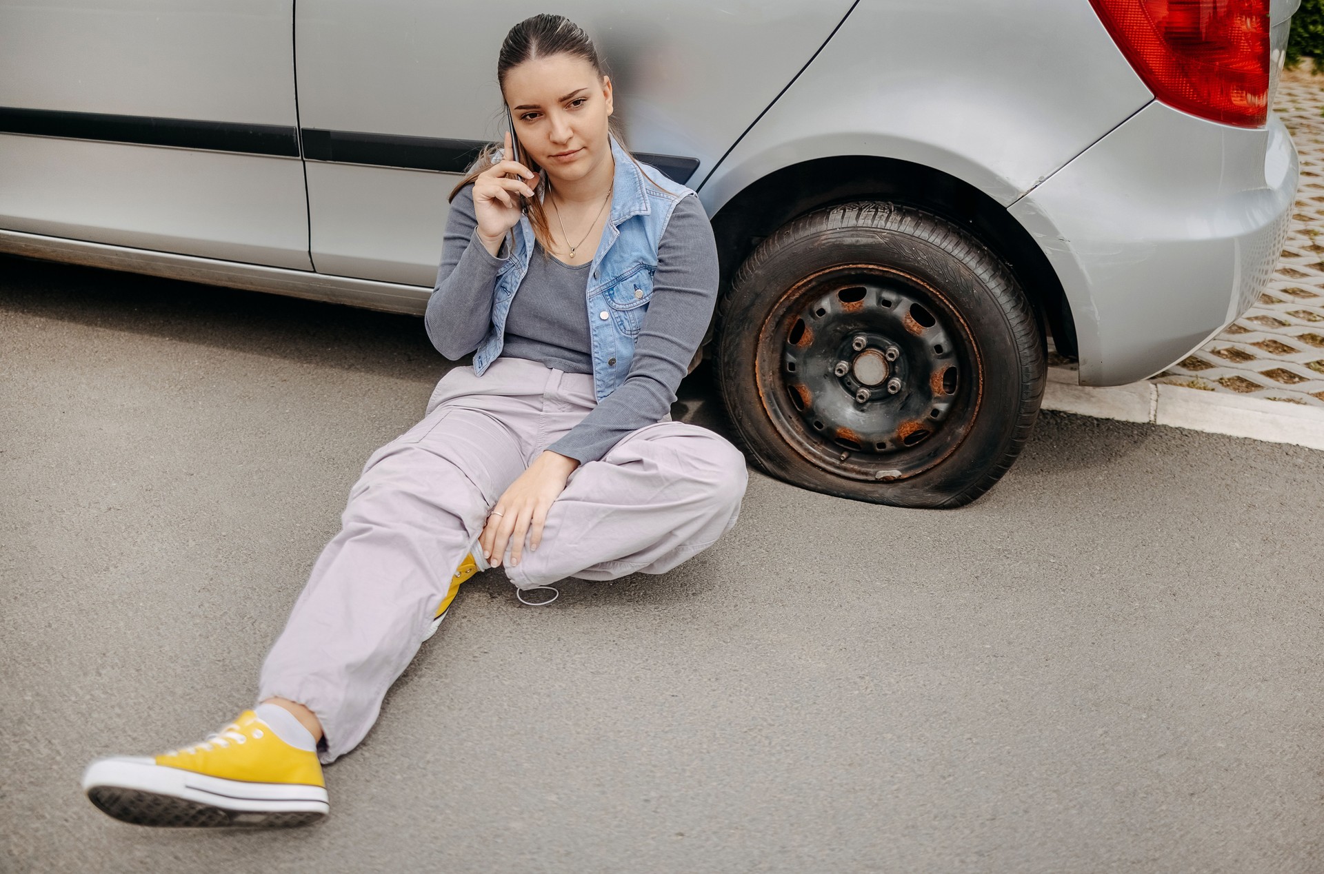 Woman having flat tyre and using mobile phone to ask for help